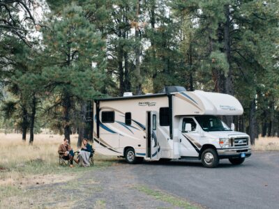 rv washer dryer combo - couple sitting on camp chairs next to their RV near a forest