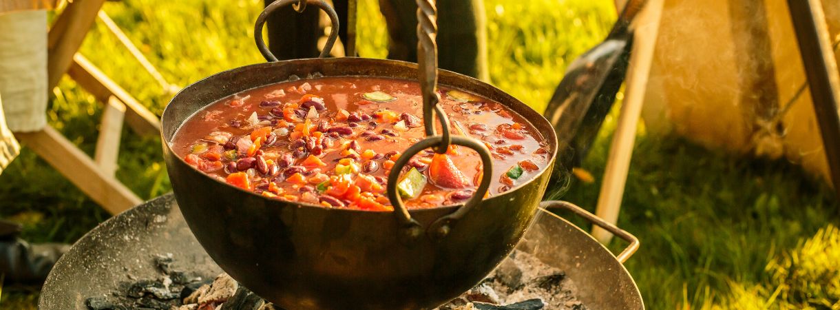 Hearty stew cooking over a fire in a tent.