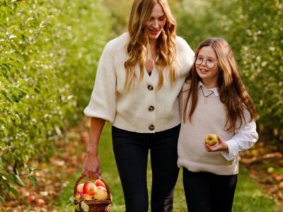 Mother with daughter picking apples in an orchard