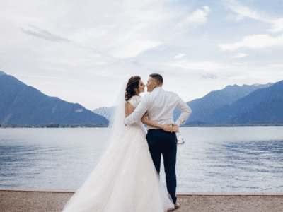 Bride and groom by the mountainous blue lakeshore.