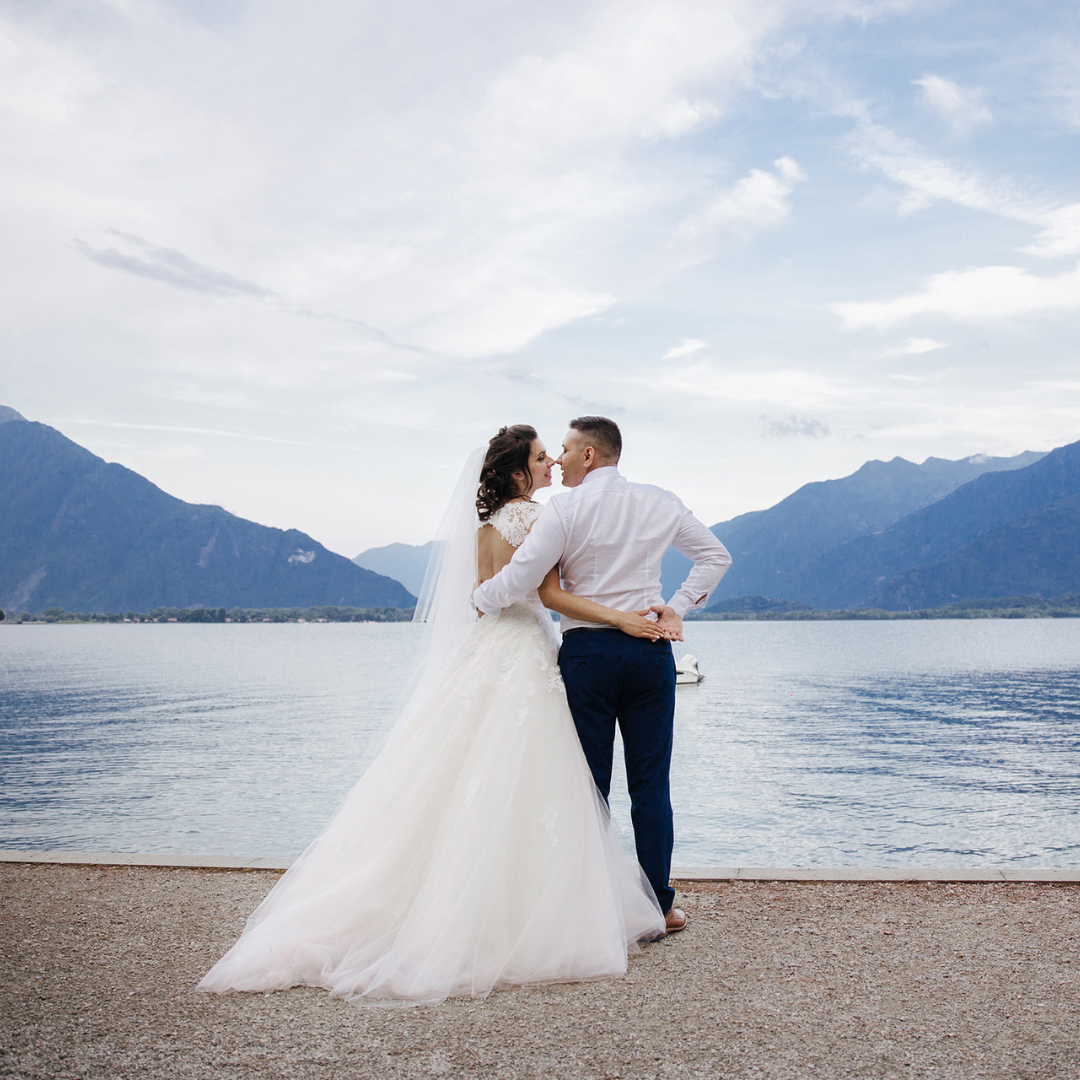 Bride and groom by the mountainous blue lakeshore.